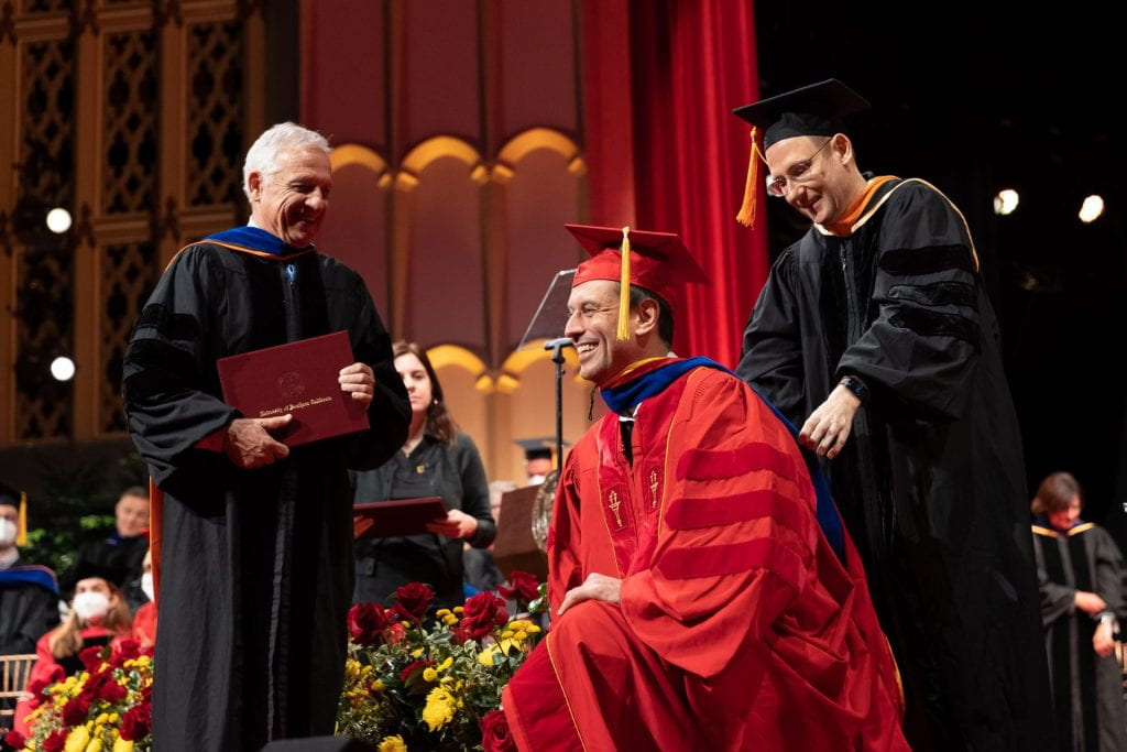 Ph.D. student receives a doctoral hood in a commencement event.